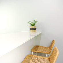 Small black basket styled on kitchen island bench with rattan bar stools